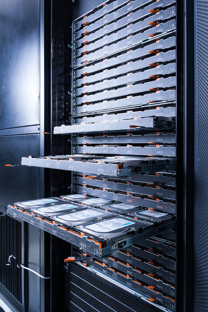 close up of hard disk drives inside hosting center - server rack filled with trays full of data storage drives - Photo, Image