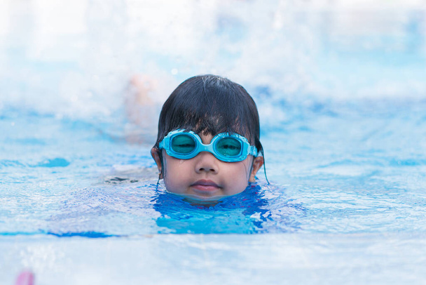 enfants heureux Souriant mignonne petite fille dans des lunettes de soleil dans la piscine. - Photo, image