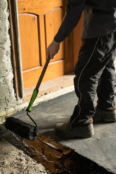 Waterdicht maken van de vloer in een privéwoning, aanbrengen van vloeibaar hars op de vloer, betonvloeren en waterdicht maken, repareren en bouwen. - Foto, afbeelding