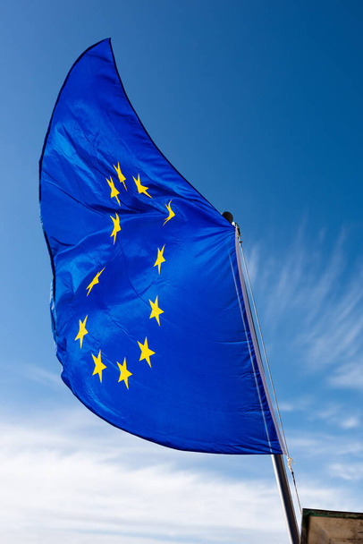 Közelkép egy európai uniós zászlóról, amely a tiszta kék égbolttal szemben integet felhőkkel és fénymásolási helyekkel. - Fotó, kép