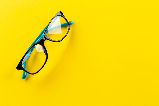 Stylish eyeglasses over yellow background. Glasses selection, eye test, vision examination at optician, fashion accessories concept. Top view, flat lay. Space for text. - Foto, Imagem