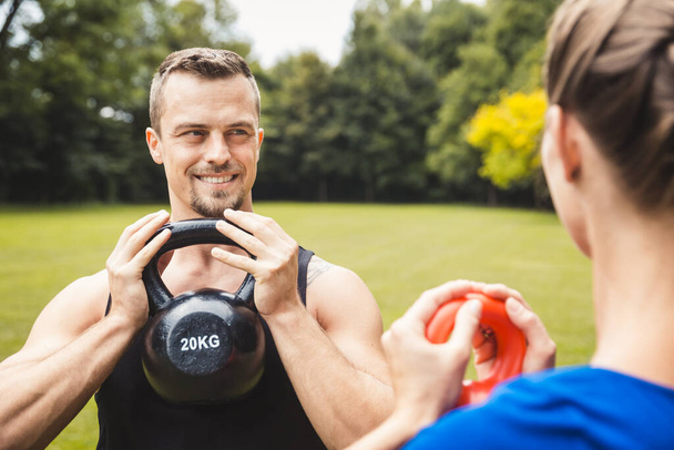 Hombre feliz haciendo ejercicio en el parque con entrenador - Foto, Imagen