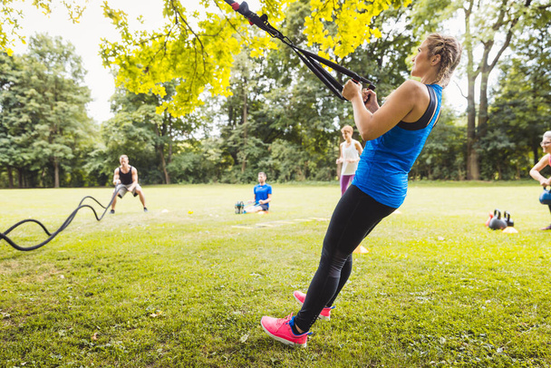 Mujer joven haciendo ejercicio con banda elástica en el parque - Foto, imagen