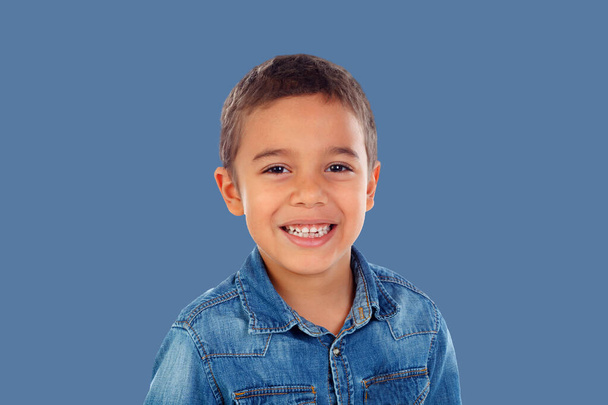 Latynoskie dziecko w dżinsowej koszuli patrzące w kamerę i śmiejące się na niebieskim tle  - Zdjęcie, obraz