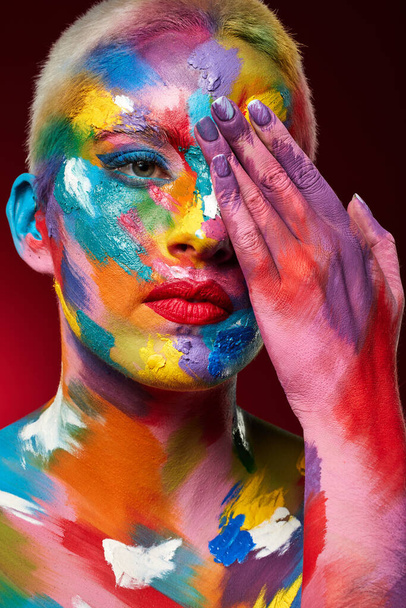 Theres a reason we dont see the world in black and white. Studio shot of a young woman posing with multi-coloured paint on her face. - Фото, изображение