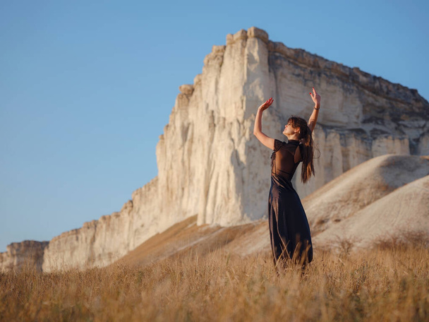 Fashionable woman on desert field near mountain wearing black dress. Wild west. Summer holidays dance. - Foto, Imagem