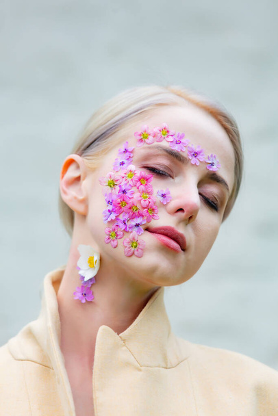 Beautiful woman with flowers petals on face on white background - Foto, Bild