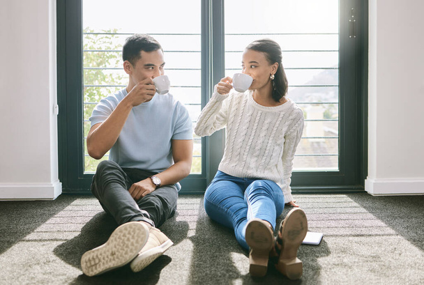 Our first cup of tea in our new home. Full length of a young couple sitting together in their new home and enjoying a cup of tea. - 写真・画像