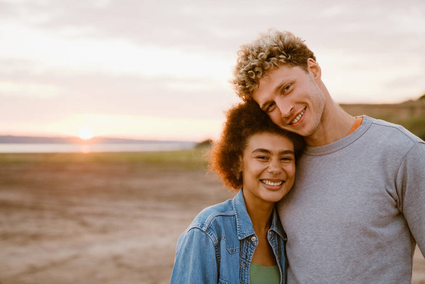 Young multiracial couple hugging and smiling while standing together outdoors - Foto, Imagem