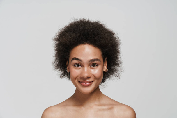 Black curly shirtless woman smiling and looking at camera isolated over white background - Zdjęcie, obraz
