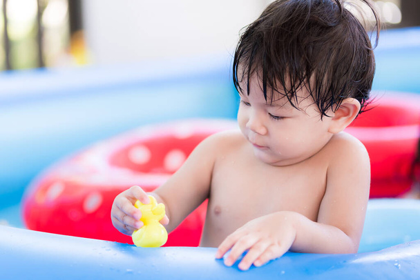 Retrato de bebé de 1-2 años. Niño jugando al pato amarillo de goma. Niño jugando al agua en la piscina. En la temporada de verano. Feliz tiempo de actividad. Los niños juegan en el agua para refrescarse del clima. Espacio vacío. - Foto, imagen