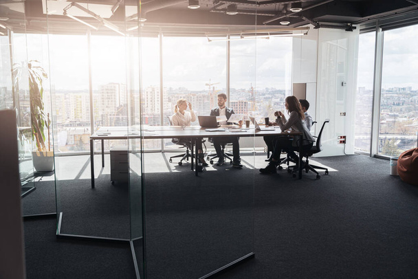 Zespół biznesmenów komunikujących się w nowoczesnym biurze z oknami panoramicznymi - Zdjęcie, obraz