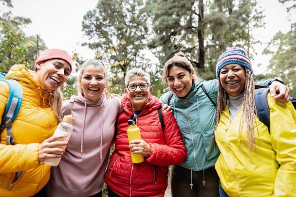 Gruppe von Frauen unterschiedlichen Alters und unterschiedlicher ethnischer Zugehörigkeit, die Spaß am Spazierengehen in den Wäldern haben - Konzept für Abenteuer- und Reisemenschen - Foto, Bild