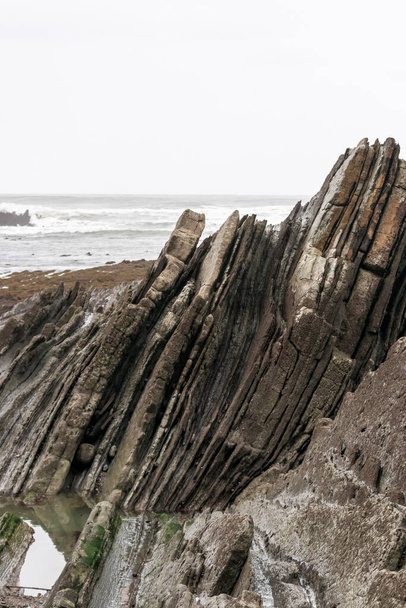 Bask bölgesindeki Sopelana plajında katmanlanmış kayalar. - Fotoğraf, Görsel