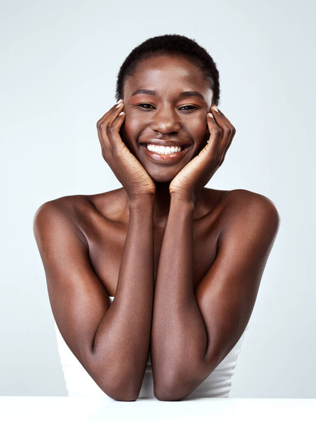 Healthy skin is something to be happy about. Studio portrait of a beautiful young woman feeling her skin against a grey background. - Foto, Imagen
