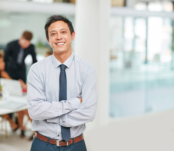 Luottavainen bisnesälyynsä. Muotokuva hymyilevä nuori liikemies seisoo kädet ristissä modernissa toimistossa. - Valokuva, kuva