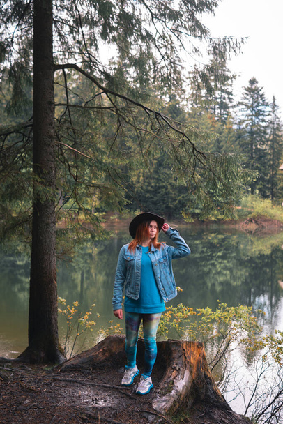 Menina turística feliz em chapéu de couro em um synevyr lago de montanha. Cárpatos, Ucrânia. Viagens e férias Europa. Dia de verão. Foto vertical. - Foto, Imagem
