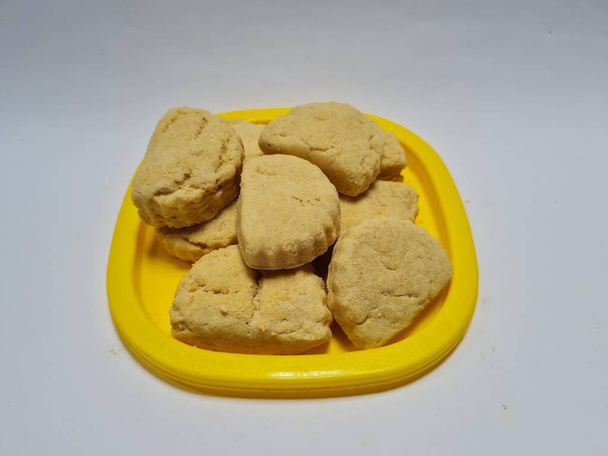 Эта сладкая закуска называется саго производится из муки и других ингредиентов, которые коричневого цвета в желтом контейнере - Фото, изображение