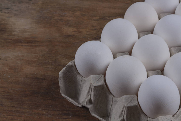 Chicken eggs close-up in a gray corton box on a wooden table - Foto, imagen