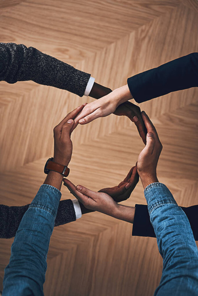 There is more power in unity than division. High angle shot of a group of unidentifiable businesspeople forming a circle with their hands. - Photo, Image