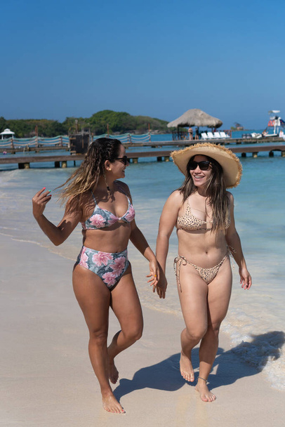 Women enjoying summer vacations on beach. - Фото, изображение