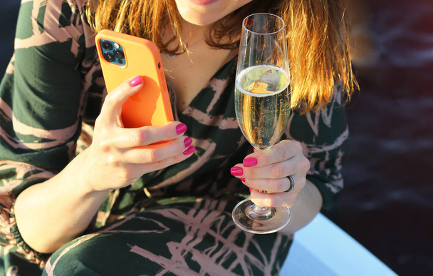 A girl on a yacht with a glass of champagne takes a selfie on a mobile phone. Rest and relaxation. Holiday and vacation. - Photo, Image