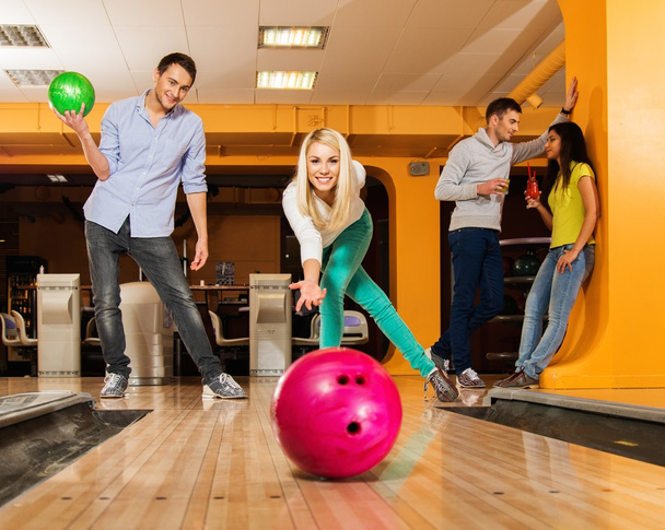 Blond smiling girl throwing ball in a bowling club   - Фото, изображение