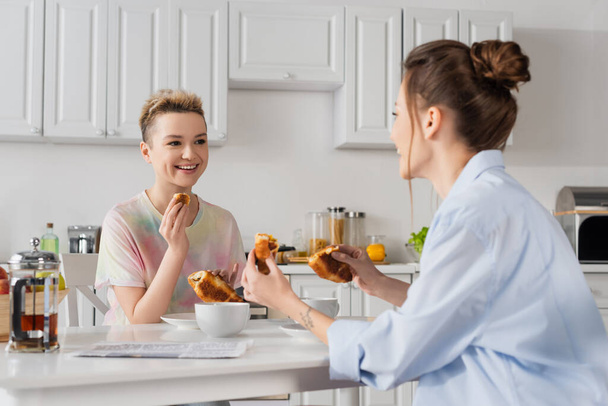 iloinen pansexual pari syö herkullisia croissantteja aamiaiseksi - Valokuva, kuva