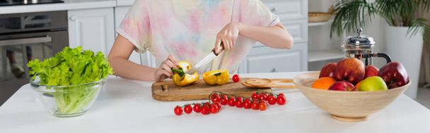 vista cortada da mulher cortando pimentão perto de tomates cereja, alface e frutas frescas, bandeira - Foto, Imagem