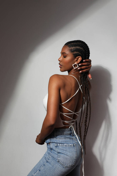 Side view portrait of African young woman with braids posing on grey background. - 写真・画像