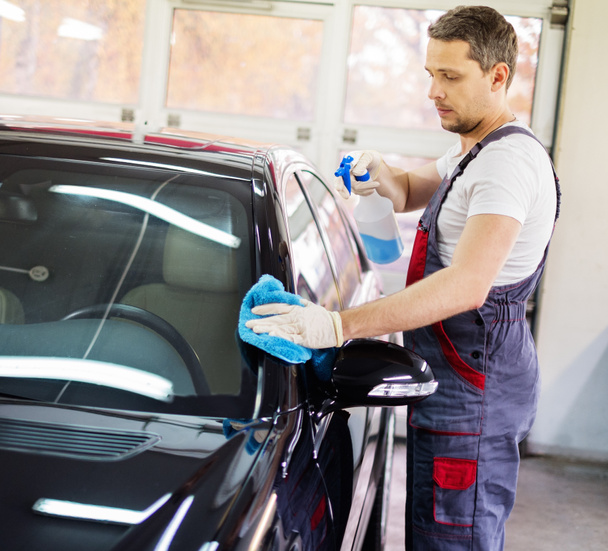 Werknemer op een auto wassen auto met een spray reiniging - Foto, afbeelding