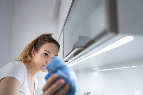 Pretty, young woman cleaning her modern,  bright kitchen - Foto, Bild