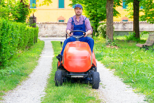 Professional lawn mower worker cutting grass in home garden - Foto, Imagen