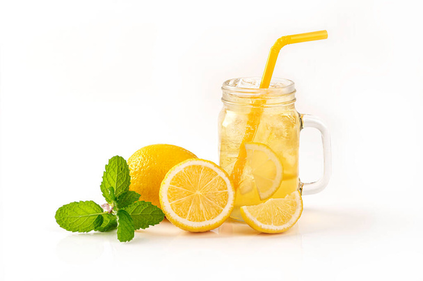 Jug of fresh lemon juice with  lemon pieces and mint leaves isolated on white background - Fotó, kép