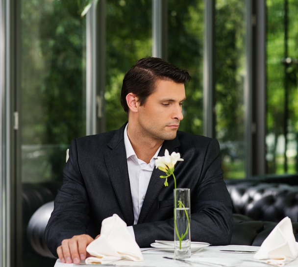 Красивий чоловік в куртці чекає когось в ресторані
  - Фото, зображення