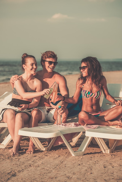 Gruppo di amici multietnici che prendono il sole su una sdraio su una spiaggia
  - Foto, immagini