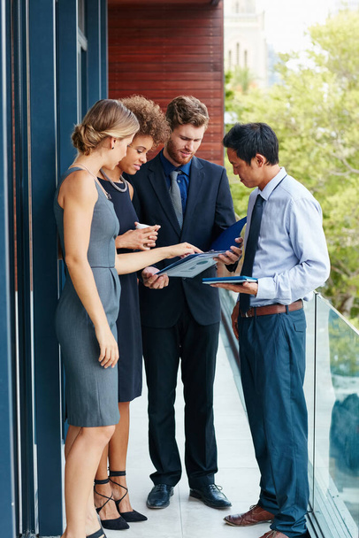 Step outside the box and have a meeting outside. Shot of a group of professionals using a digital tablet together outside of the office. - Foto, imagen