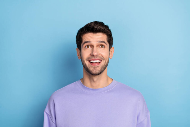 Photo of impressed millennial brunet guy look up wear sweatshirt isolated on blue color background - Photo, image