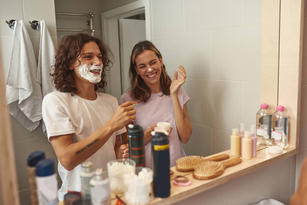 Guy smearing foam on girlfriend nose while shaving - Foto, afbeelding