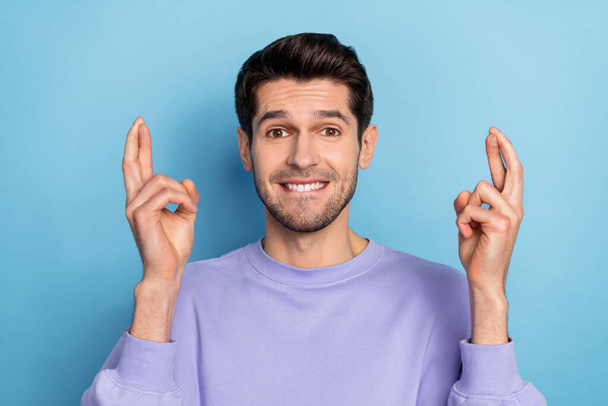 Photo of stressed millennial brunet guy crossed fingers wear sweatshirt isolated on blue color background - Photo, image