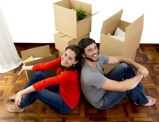 happy couple moving together in a new house unpacking cardboard boxes  - Photo, Image