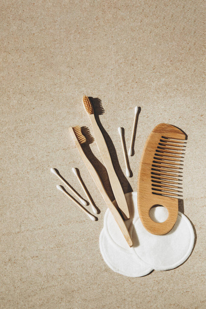 2本の木の歯ブラシ、綿のパッドとスティック、光の背景に木製のヘアブラシ - 写真・画像