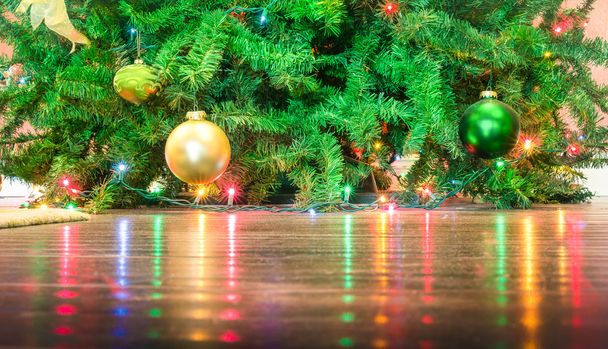 Λεπτομέρεια των διακοσμήσεων χριστουγεννιάτικων δέντρων με φώτα αντανακλάσεις στο πάτωμα - περικοπεί σύνθεση για διακοπές φόντο - Φωτογραφία, εικόνα