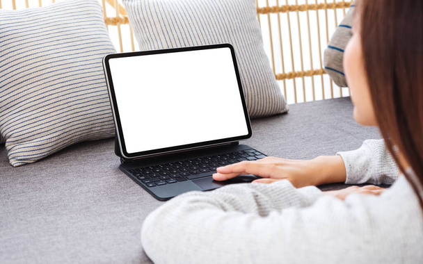 Образец изображения женщины, использующей планшетный компьютер с чистым рабочим столом белый экран в качестве компьютера ПК на диване дома - Фото, изображение