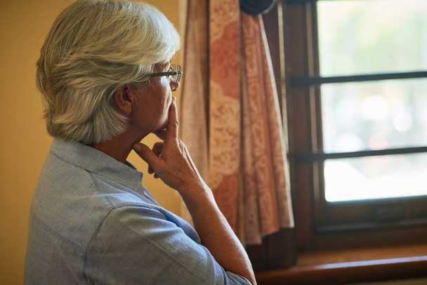 Taking some time to reflect deeply. Cropped shot of a senior woman looking out the window at home. - Photo, image