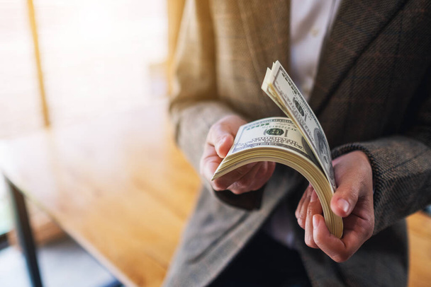 Εικόνα κλεισίματος μιας γυναίκας που κατέχει και μετρά τραπεζογραμμάτια αμερικανικού δολαρίου για χρήμα και οικονομική έννοια - Φωτογραφία, εικόνα