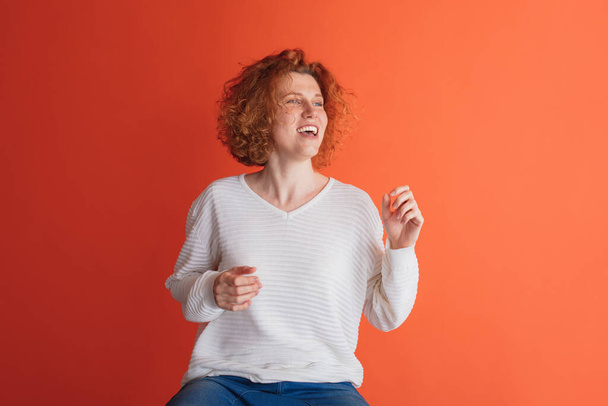 Portrait of happy looking red-haired woman cheerfully posing isolated over red studio background - Foto, Bild