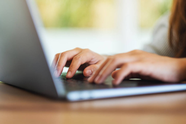 Zbliżenie obrazu młodej kobiety pracującej i piszącej na klawiaturze komputera na laptopie na drewnianym stole - Zdjęcie, obraz
