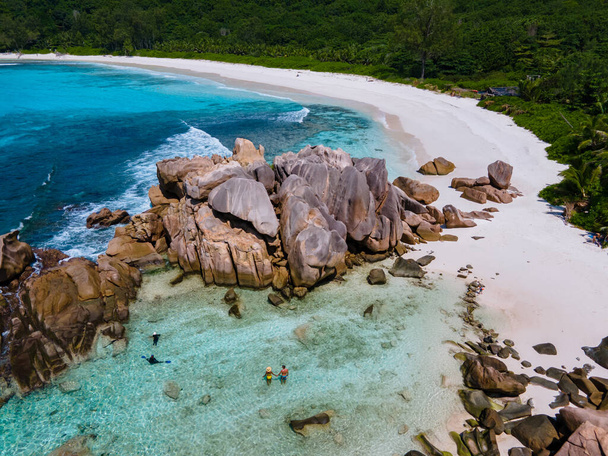 Anse Cocos strand, La Digue Island, Seyshelles, Drone légi kilátás a La Digue Seychelles madártávlatból, pár férfi és nő sétál a strandon napnyugtakor egy luxus nyaralás - Fotó, kép