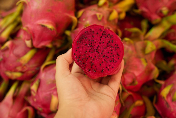 In the mood for something exotic. Shot of an unidentifiable woman holding a halved dragon fruit at a fruit market. - Foto, Imagen